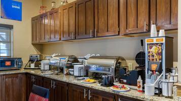 A buffet setup with various food stations, including a waffle maker and a beverage dispenser.