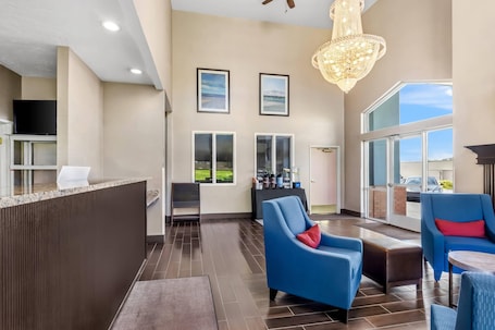 A spacious lobby with a reception desk, seating area, large windows, and a chandelier.