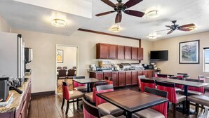 A restaurant with multiple tables and chairs, ceiling fans, a kitchen area, and a television. - Comfort Inn Elko (Elko)
