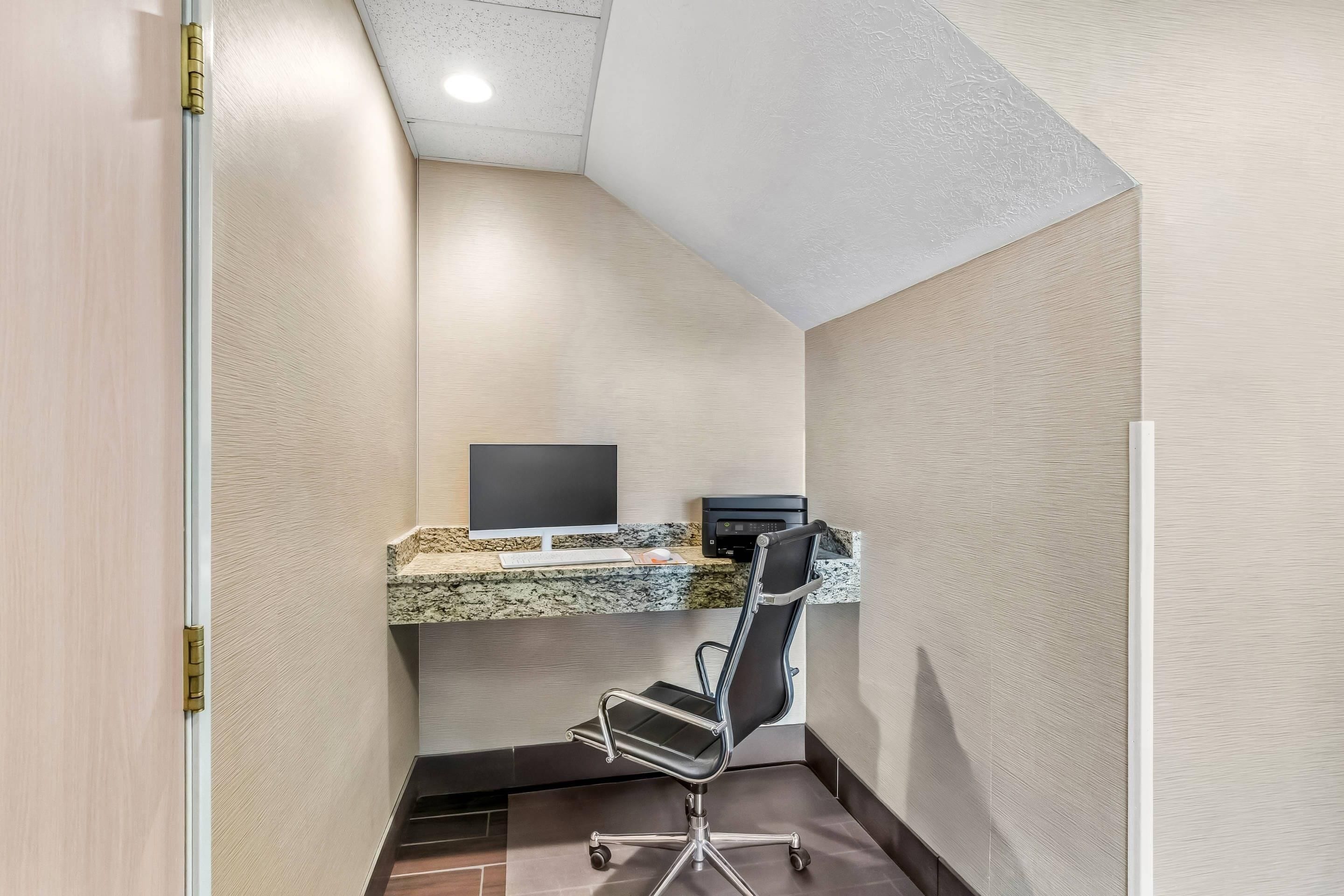 A corner office with a desk, chair, and a computer monitor.