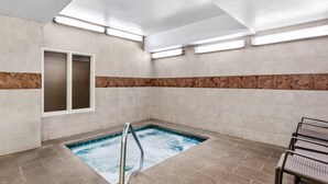 A spa area with a hot tub, a glass door, and a seating area with chairs. - Comfort Inn Elko (Elko)