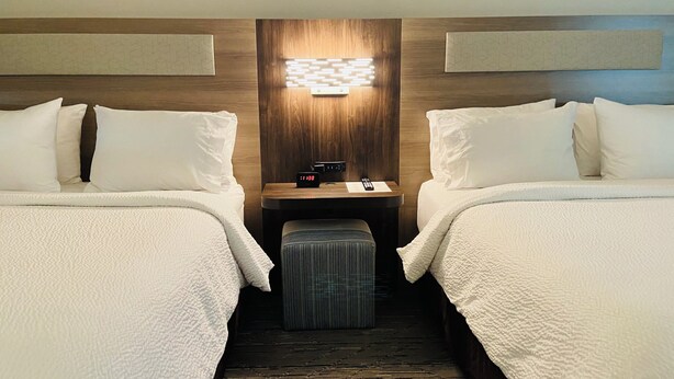 A hotel room with two beds, a nightstand with a clock, and a wall-mounted light fixture. - Holiday Inn Express Bluffton by IHG (Bluffton)