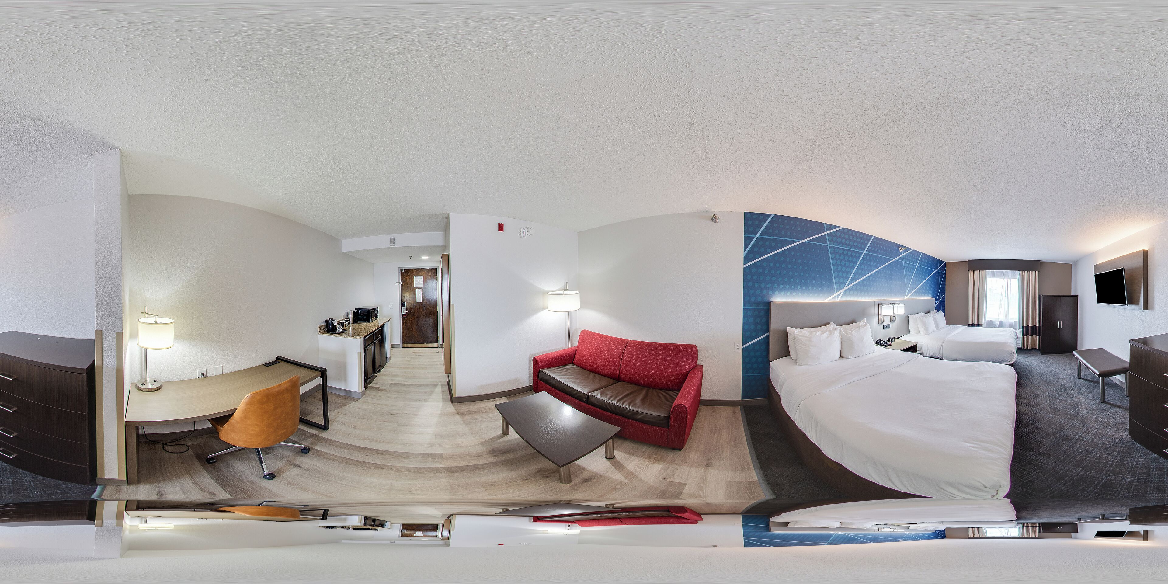 Une chambre d’hôtel moderne, dotée d’un bureau, d’un canapé rouge et d’un grand lit.