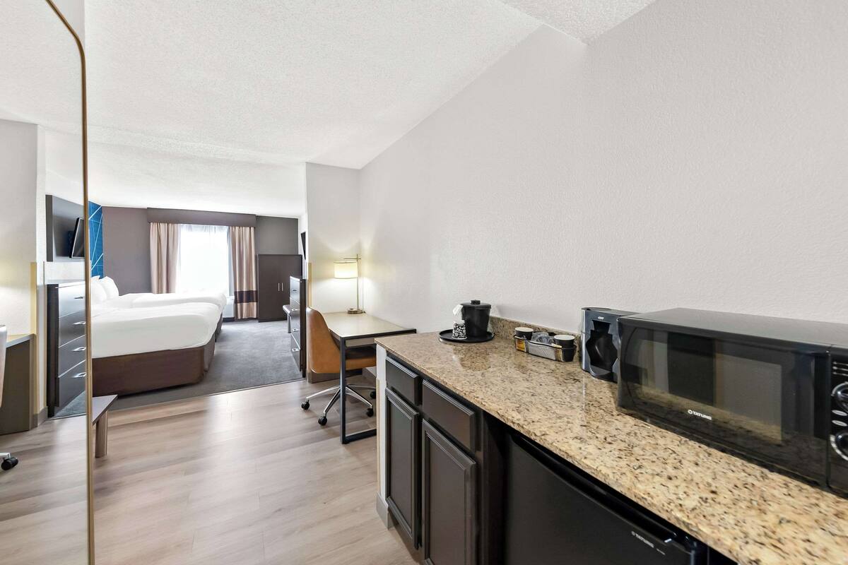 A hotel room with a bed, a desk, a microwave, and a coffee maker.