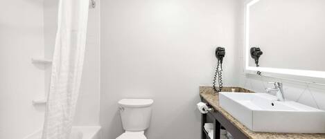 Een badkamer met een bad, toilet en een wastafel met spiegel.