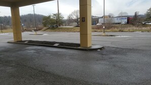 A parking lot with yellow pillars, a no parking sign, and a truck in the background. - Cambridge Inn by Capital O near I-70 / I-77 (Cambridge)