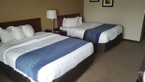 Two double beds with white and blue bedding, a bedside table with a lamp, and a plain wall with two framed pictures. - Cambridge Inn by Capital O near I-70 / I-77 (Cambridge)