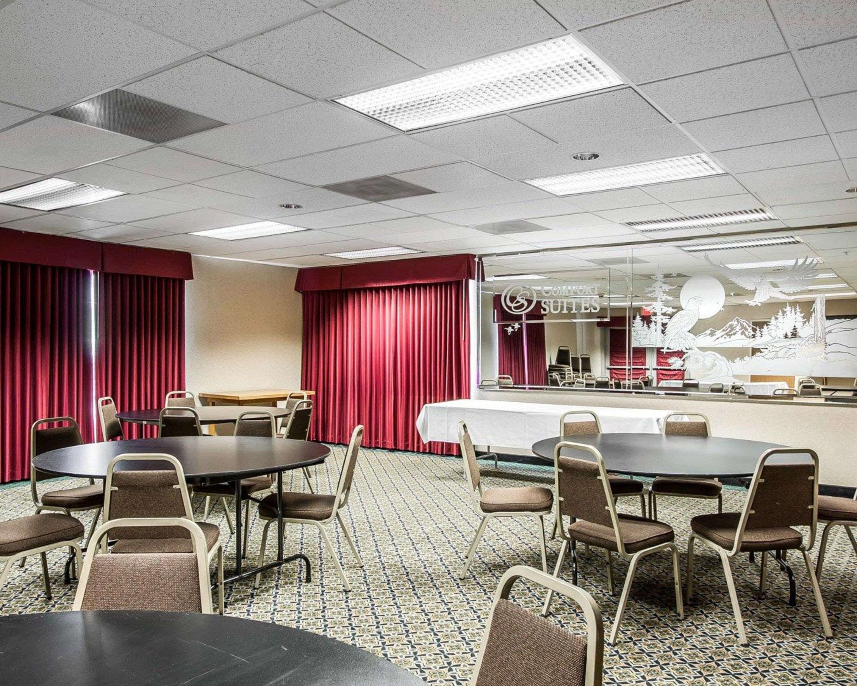 A conference room with round tables and chairs, a reception desk, and a mural on the wall.