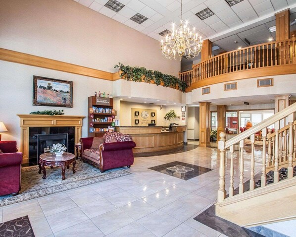 Welcome to our lobby, featuring a fireplace, comfortable seating, and a grand staircase.