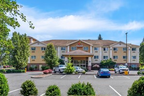 A Comfort Suites hotel with a parking lot and several cars parked in front. - Comfort Suites Clackamas (Clackamas)