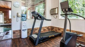 A gym with treadmills and a stationary bike, a water dispenser, and a clock on the wall.