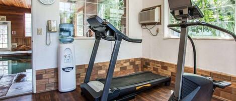 A gym with treadmills and a stationary bike, a water dispenser, and a clock on the wall.