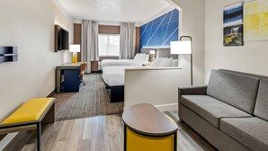 A hotel room with a bed, a sofa, a desk, and a TV. - Comfort Suites Clackamas (Clackamas)