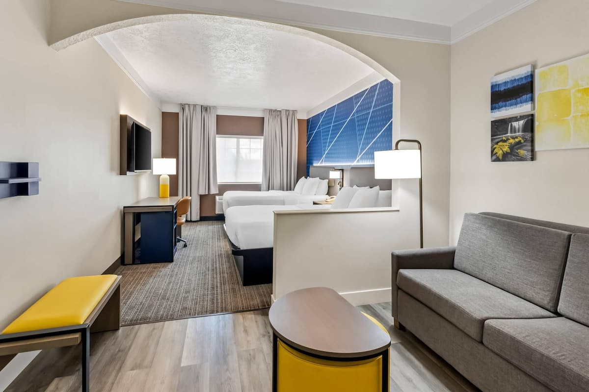 A hotel room with a bed, a sofa, a desk, and a TV.