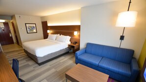 Une chambre d’hôtel avec un lit, un canapé bleu, une table basse en bois et un bureau avec une chaise.