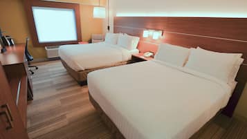 A hotel room with two beds, a desk, a chair, a desk lamp, a telephone, and a window with blinds.