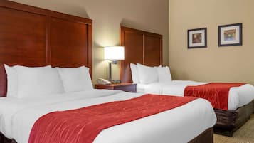 A hotel room with two beds, a nightstand with a lamp, and two framed pictures on the wall.