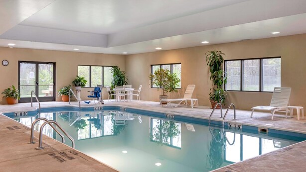 An indoor swimming pool with clear water, surrounded by lounge chairs and potted plants. - Comfort Inn Duncansville - Altoona (Hollidaysburg)
