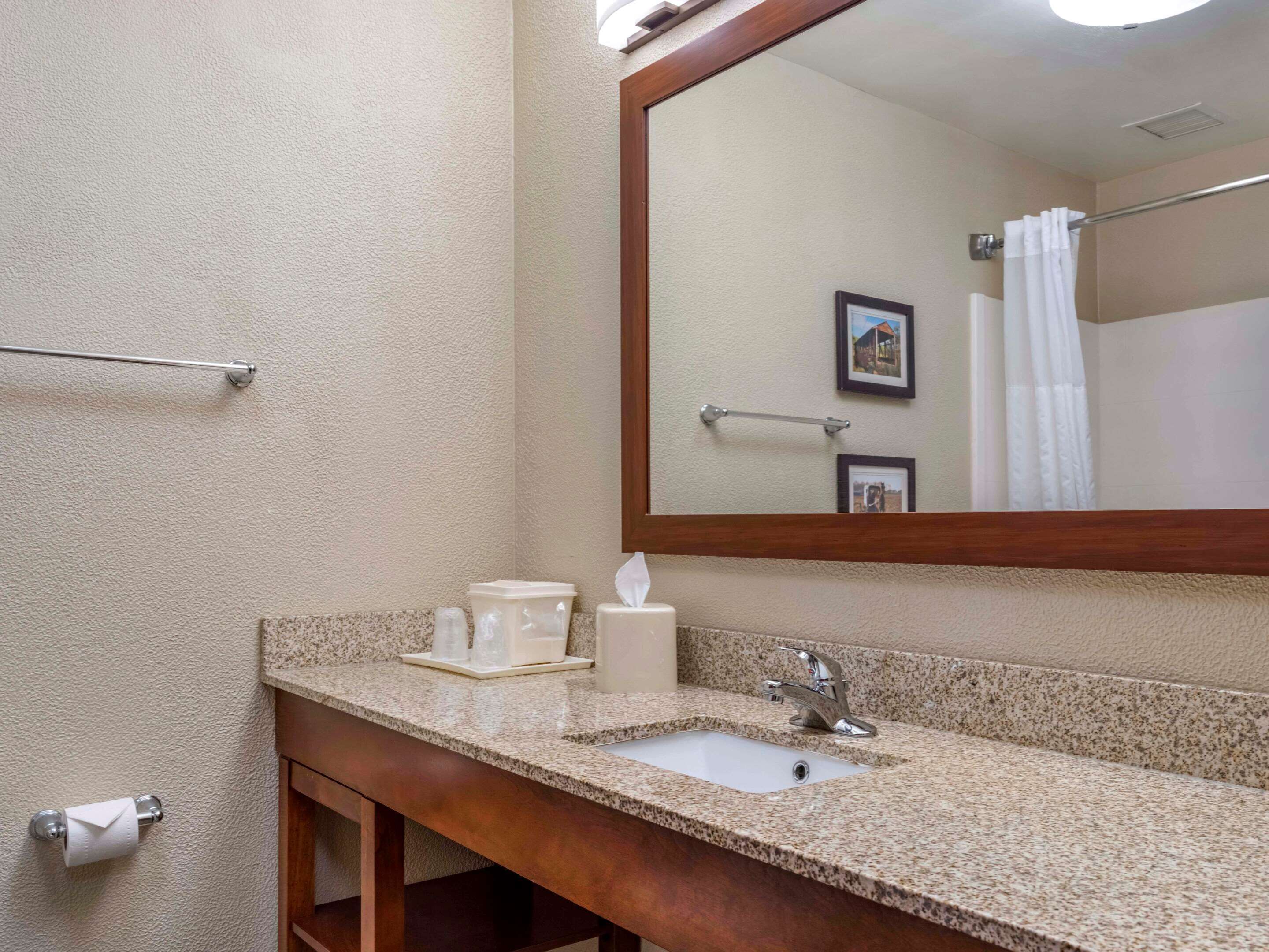 Un bagno con lavabo in granito, specchio, porta asciugamani e porta carta igienica.