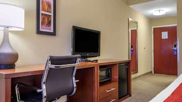 Une chambre d’hôtel équipée d’un bureau, d’une chaise, d’une télévision et d’un four à micro-ondes.