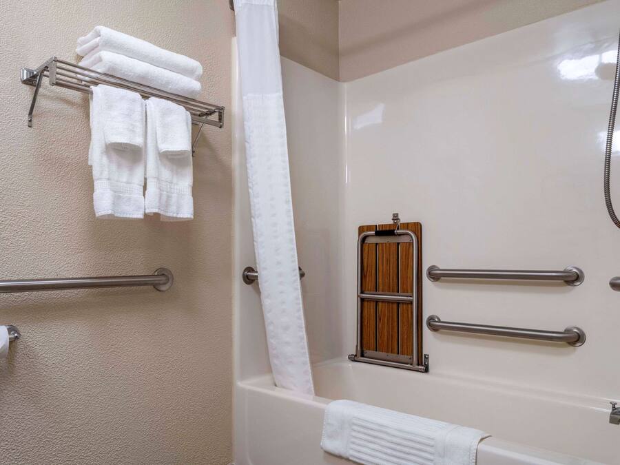 Un bagno con una vasca, una doccia e un portasciugamani con asciugamani piegati.