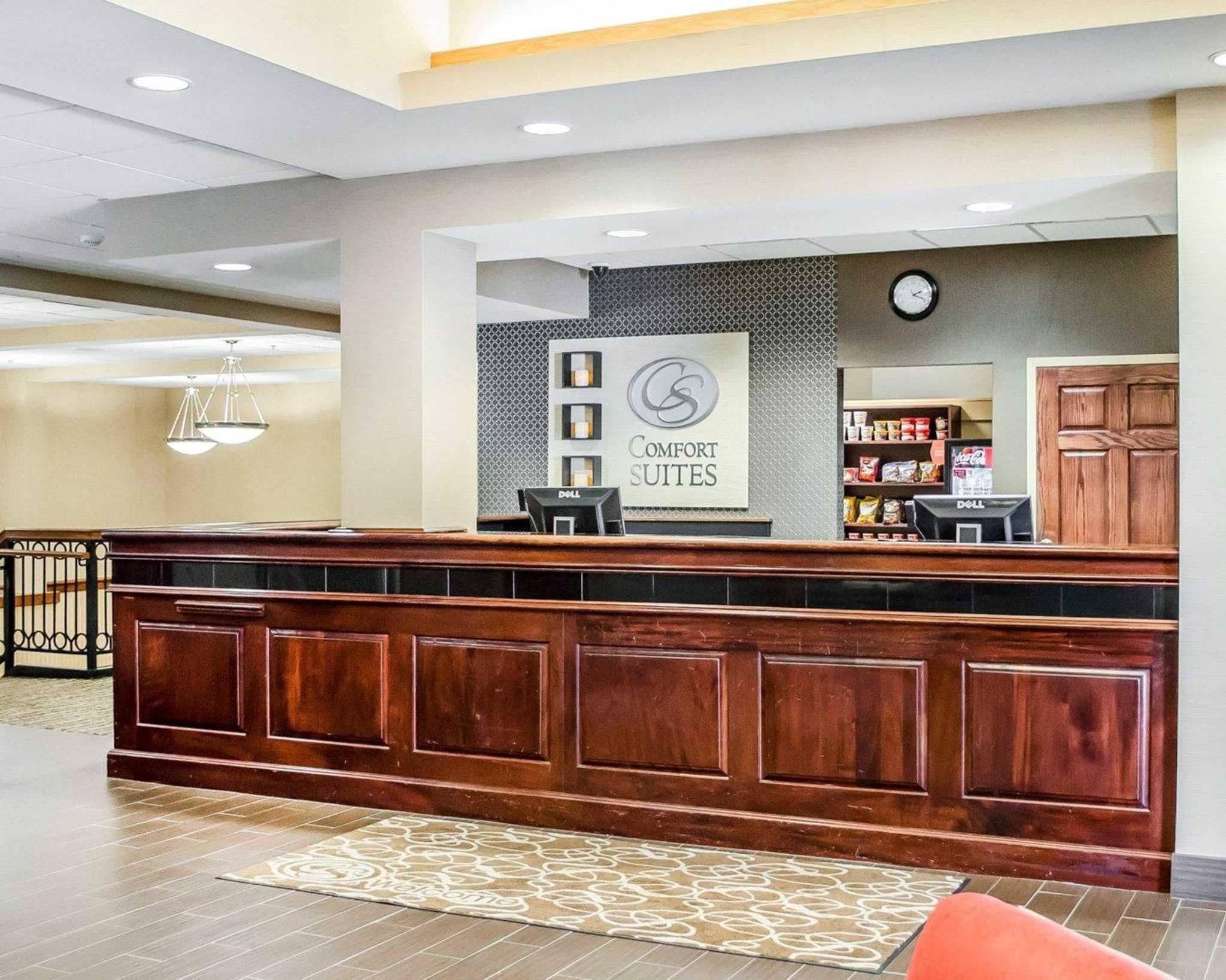 Zona de recepción con un mostrador de madera, un reloj y un cartel que dice "Comfort Suites".