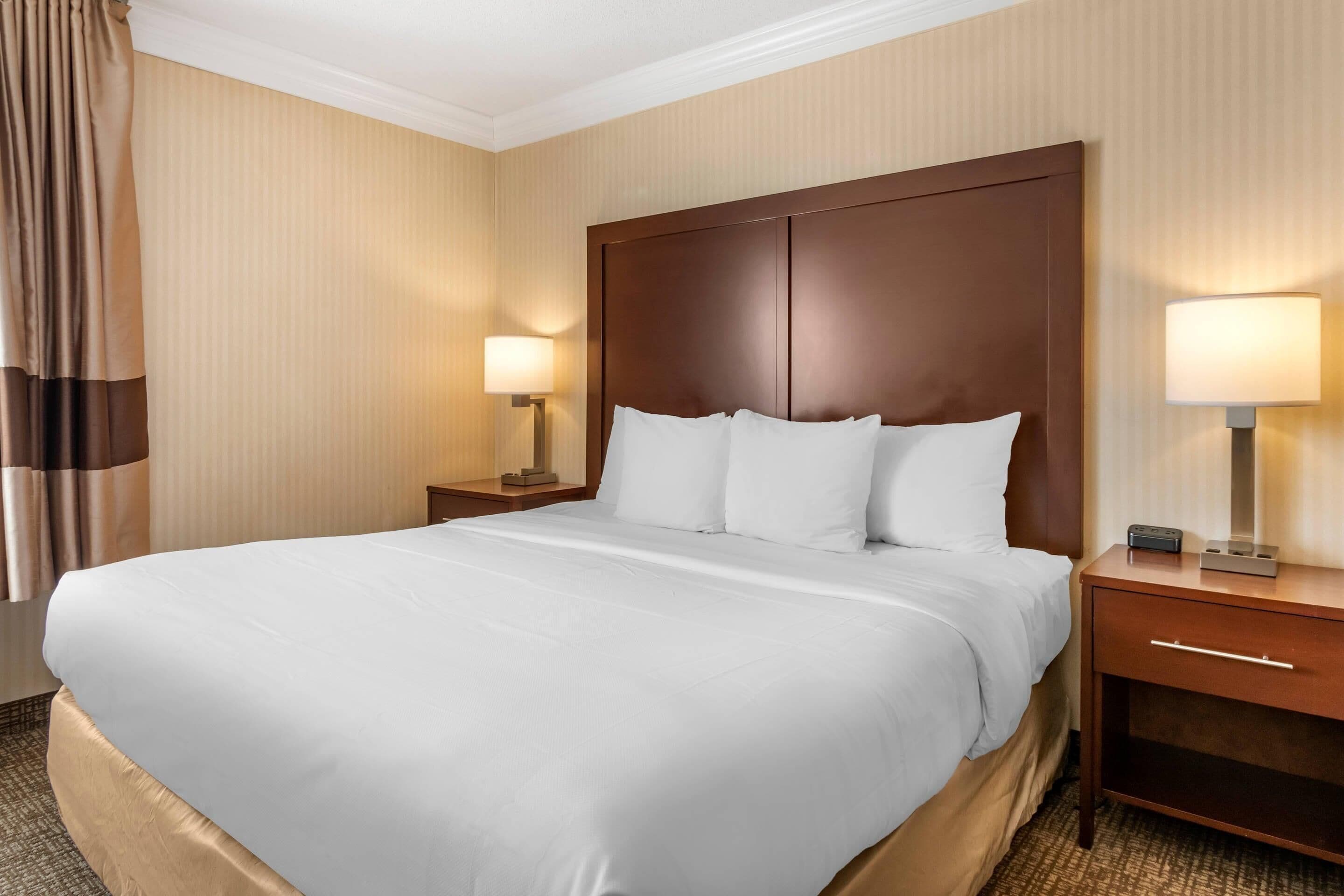 A hotel room with a large bed, two bedside tables with lamps, and a wooden headboard.