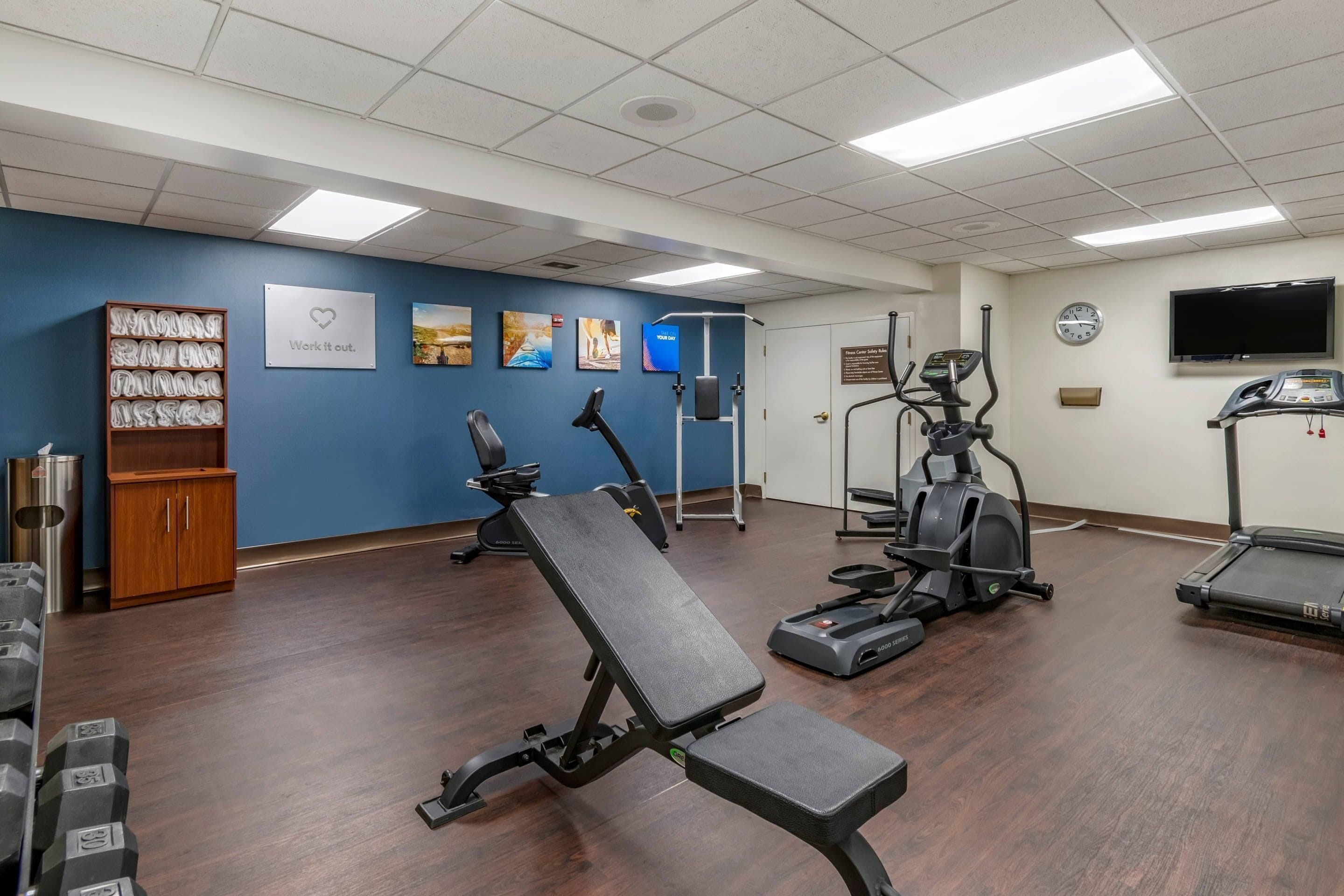 A gym with exercise equipment, a wall clock, and motivational posters.