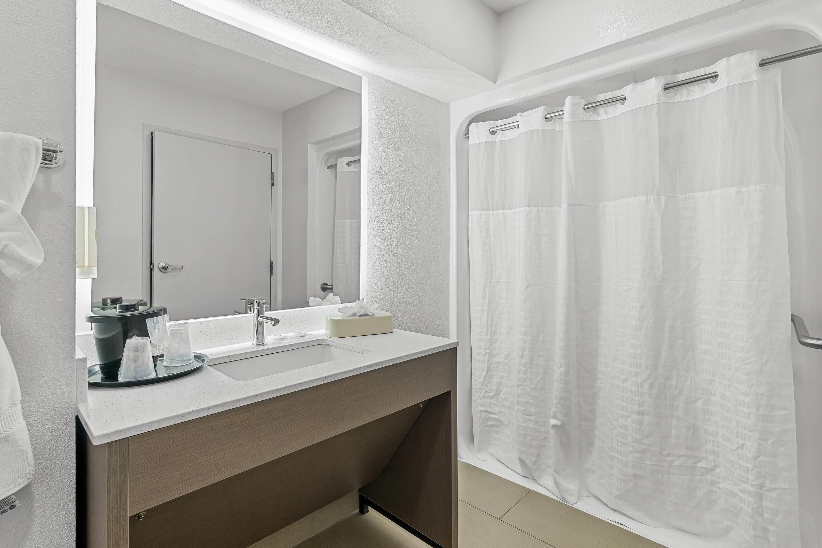 A modern bathroom with a white sink, mirror, and shower curtain.