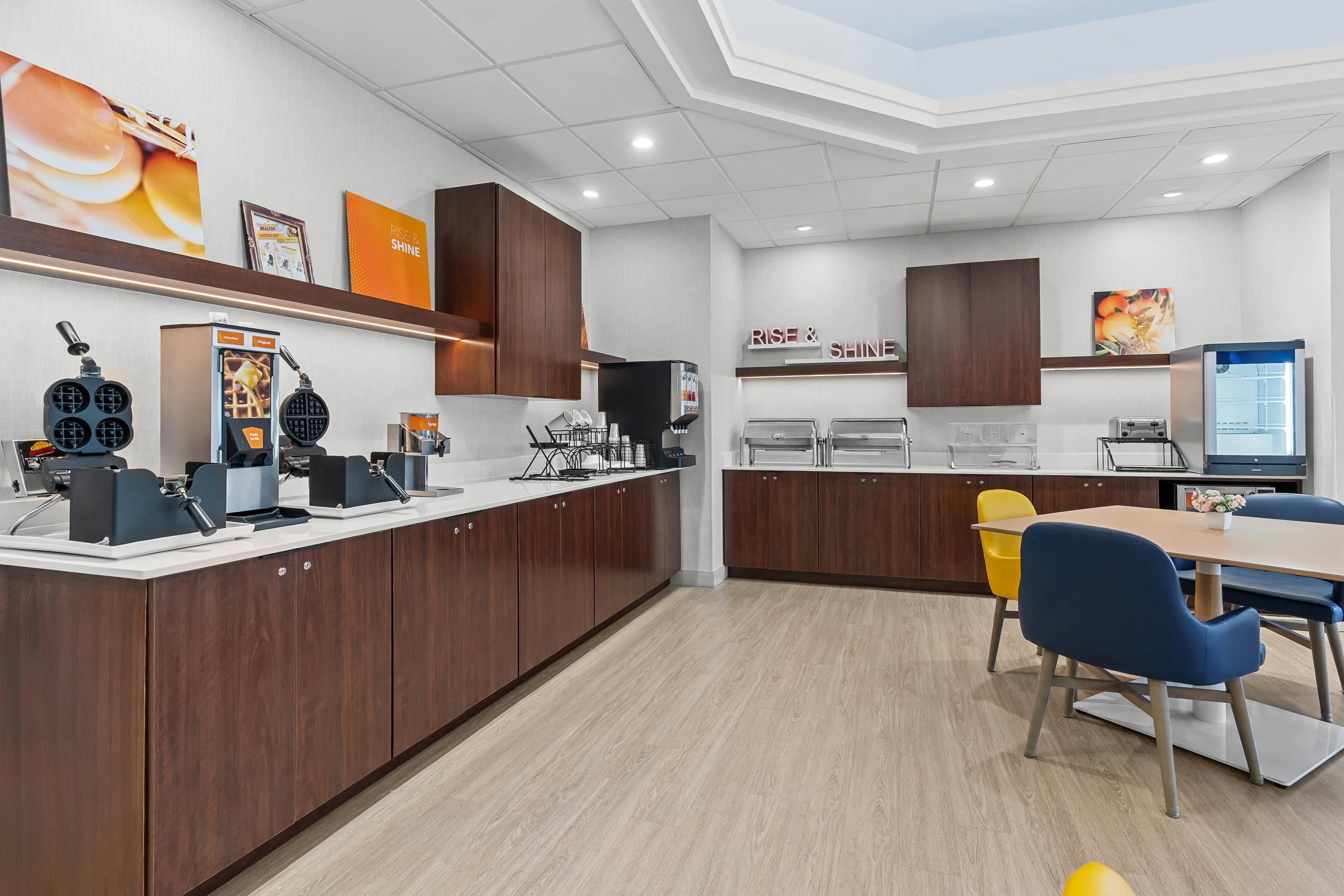 Una cocina moderna con armarios de madera oscura, encimera blanca y un área de comedor con mesa y sillas.