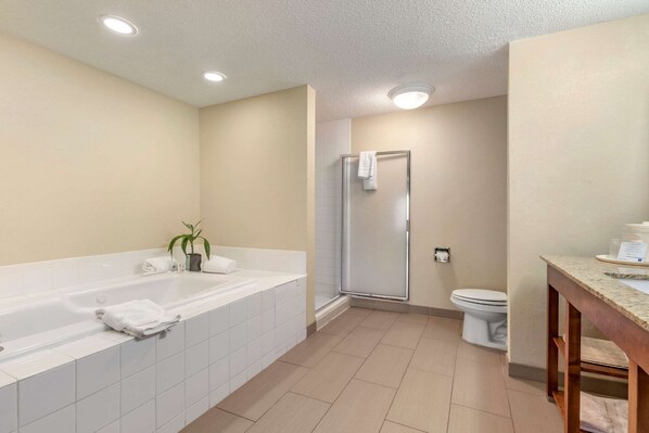 Un baño moderno con una bañera grande, ducha y retrete.