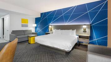 Ein modernes Hotelzimmer mit einem großen Bett, einer Couch, einem kleinen Tisch und einem Sessel.