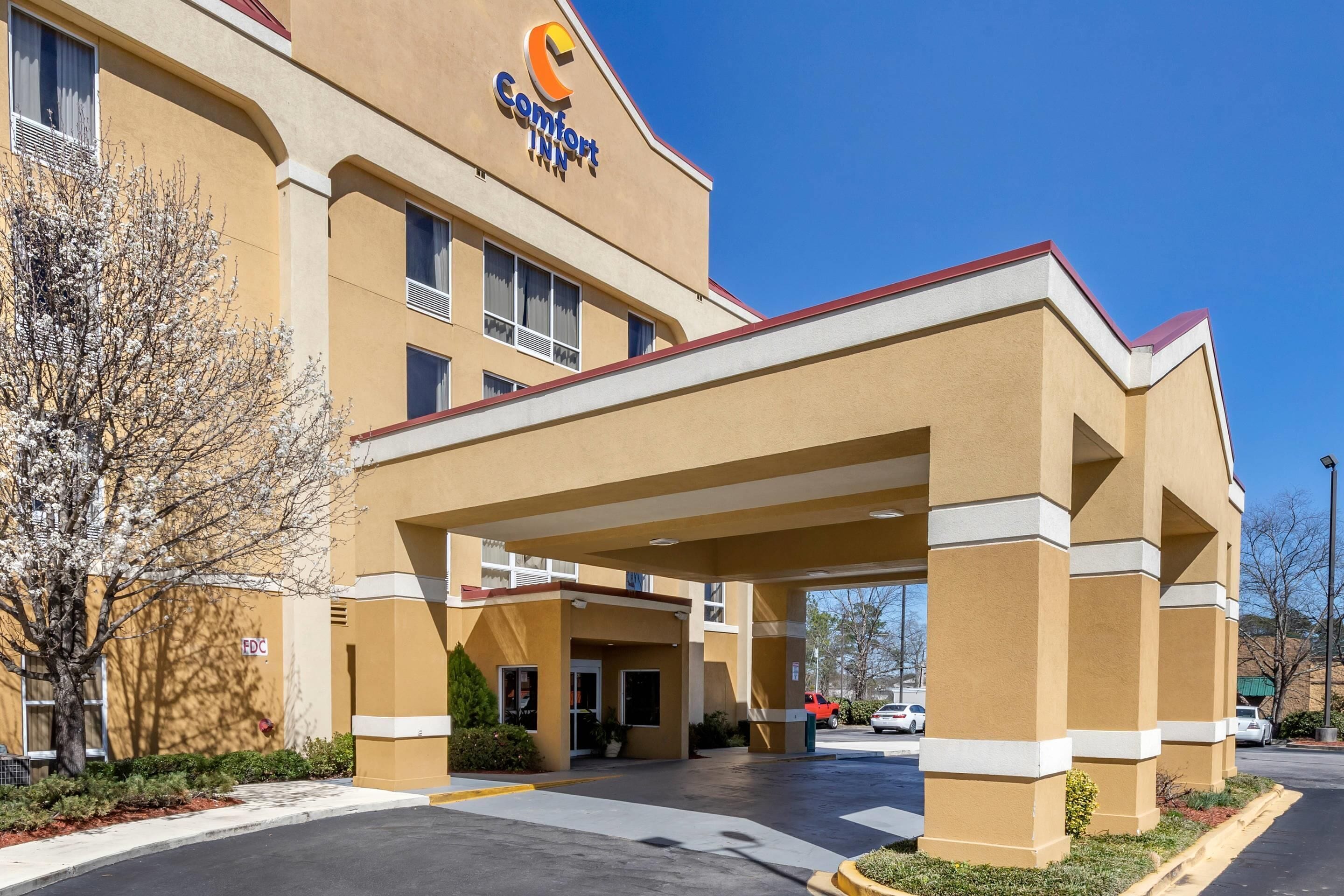 A Comfort Inn hotel with a covered entrance, a parking lot, and a clear blue sky.