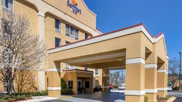 A Comfort Inn hotel with a covered entrance, a parking lot, and a clear blue sky.