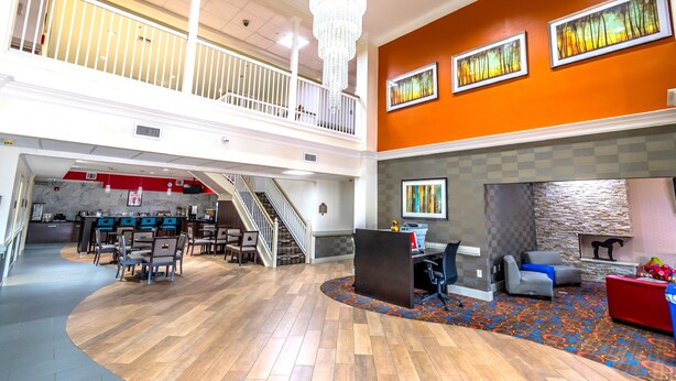 A spacious lobby with a high ceiling, a chandelier, a staircase, and a dining area. - Econo Lodge Inn & Suites East Houston I-10 (Houston)