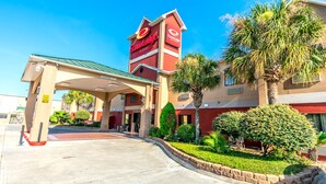 A hotel entrance with a clear sign, a covered parking area, and well-maintained landscaping. - Econo Lodge Inn & Suites East Houston I-10 (Houston)