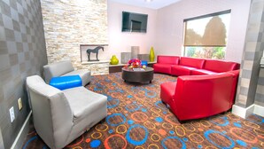 A modern living room with grey and red sofas, a patterned carpet, and a stone wall. - Econo Lodge Inn & Suites East Houston I-10 (Houston)