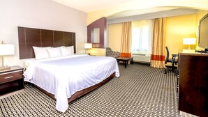 A hotel room with a large bed, a desk, a chair, a TV, and a bathroom with a shower and toilet. - Econo Lodge Inn & Suites East Houston I-10 (Houston)
