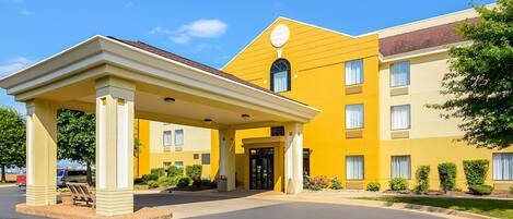 A yellow building with a covered entrance and a clear sky.