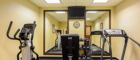 A gym with cardio machines, weights, and a treadmill.