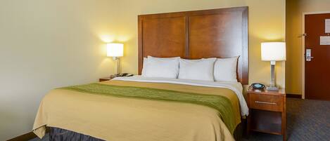 A hotel room with a large bed, two bedside tables, and a nightstand with a lamp.