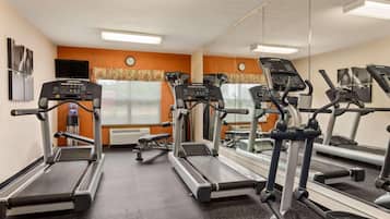 Un gimnasio con cintas de correr, espejos y un reloj en la pared.