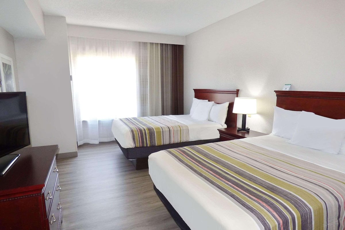 A hotel room with two beds, a TV, and a dresser.