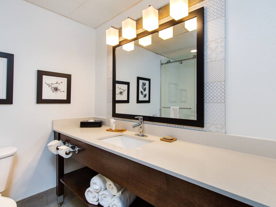 Une salle de bain moderne avec un grand miroir, un lavabo blanc et des toilettes.
