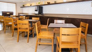 A restaurant with wooden tables and chairs, a tiled backsplash, and a trash can labeled "TRASH". - Country Inn & Suites by Radisson, Rapid City, SD (Rapid City)