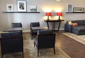 Ein Wohnzimmer mit einer Couch, zwei Sessel, einem Tisch und zwei Lampen.