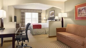 A hotel room with a bed, desk, chair, sofa, and two lamps. - Country Inn & Suites by Radisson, Tuscaloosa, AL (Tuscaloosa)