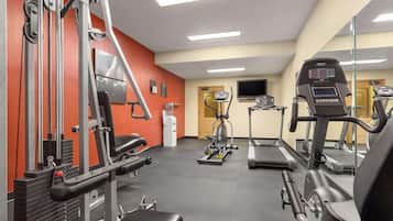 A gym with various exercise equipment, including a treadmill, elliptical, and weight machines.