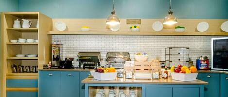A breakfast bar with a coffee machine, fruit bowl, and cereal box.