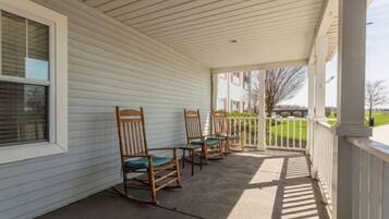 A covered porch with wooden rocking chairs and a white railing.